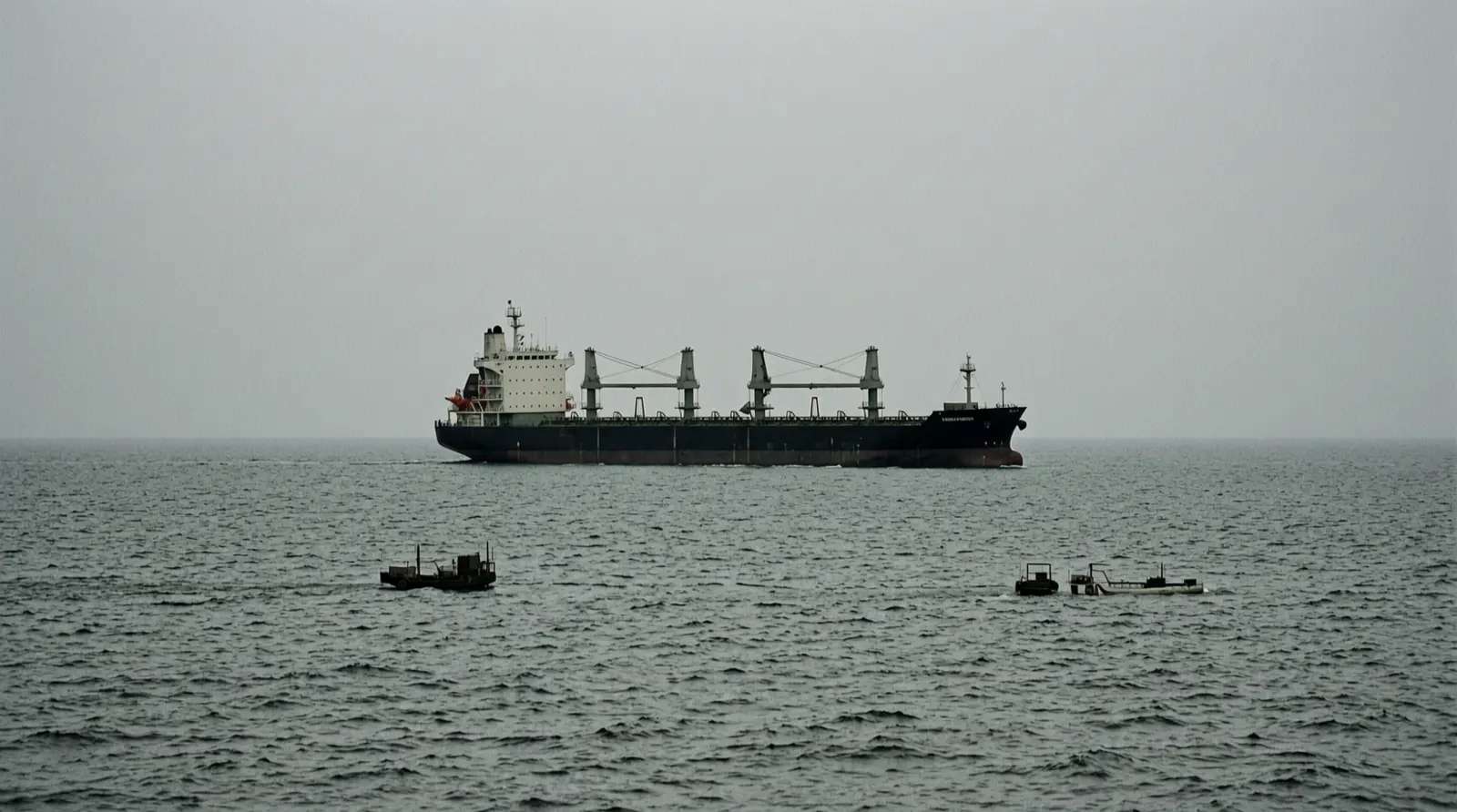 A tanker moving across open water under an overcast sky, seen from a distance.